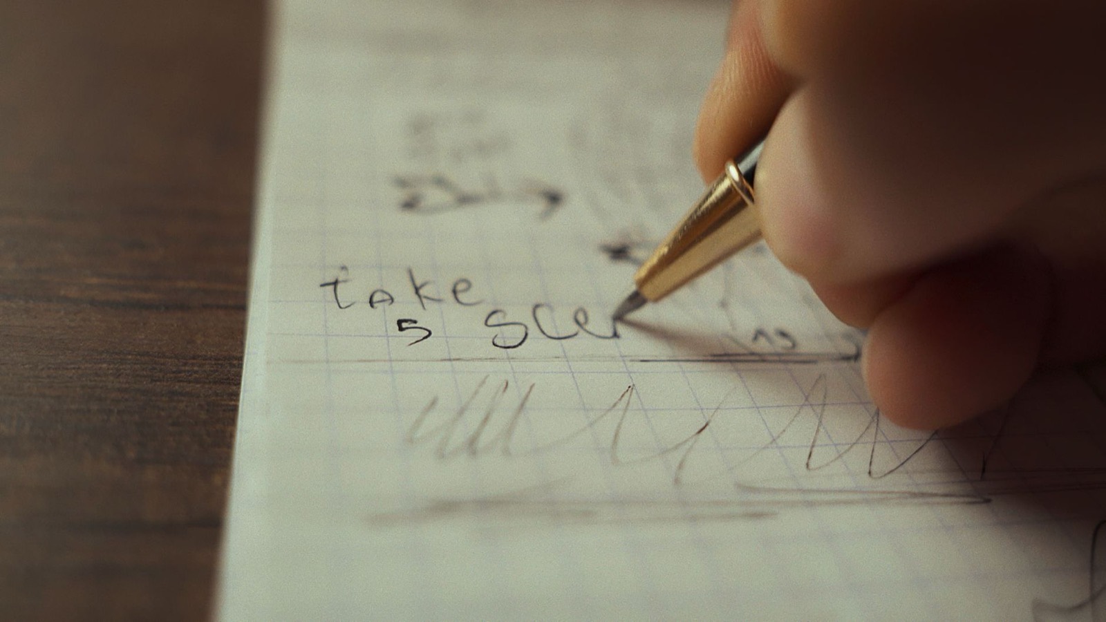 A close-up of a hand writing on graph paper with a fountain pen.